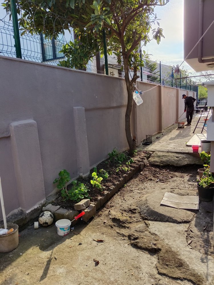 Bahçe duvarı boyanırken, rulo ile uygulama